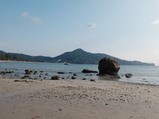 A cluster of weathered rocks sentinels of the shore with mountain and clearly sky background, Kamala beach, Phuket, Thailand.