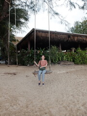 Thai woman on wooden outdoor swing at Kamala Beach, Phuket, Thailand.