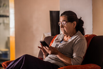 mujer adulta usando lentes y mirando su telefono movil muy concentrada 
