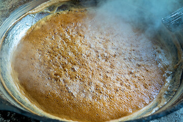 Asian man making boiled palm coconut sugar or cane production process, raw material, Indonesia. Traditional culture lifestyle. Local sweet food.