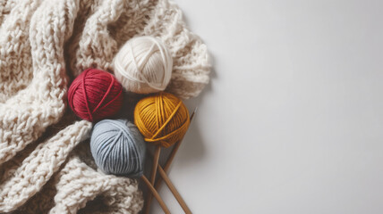 Fototapeta na wymiar Knitting yarn balls with needles and a cream scarf on a white background.