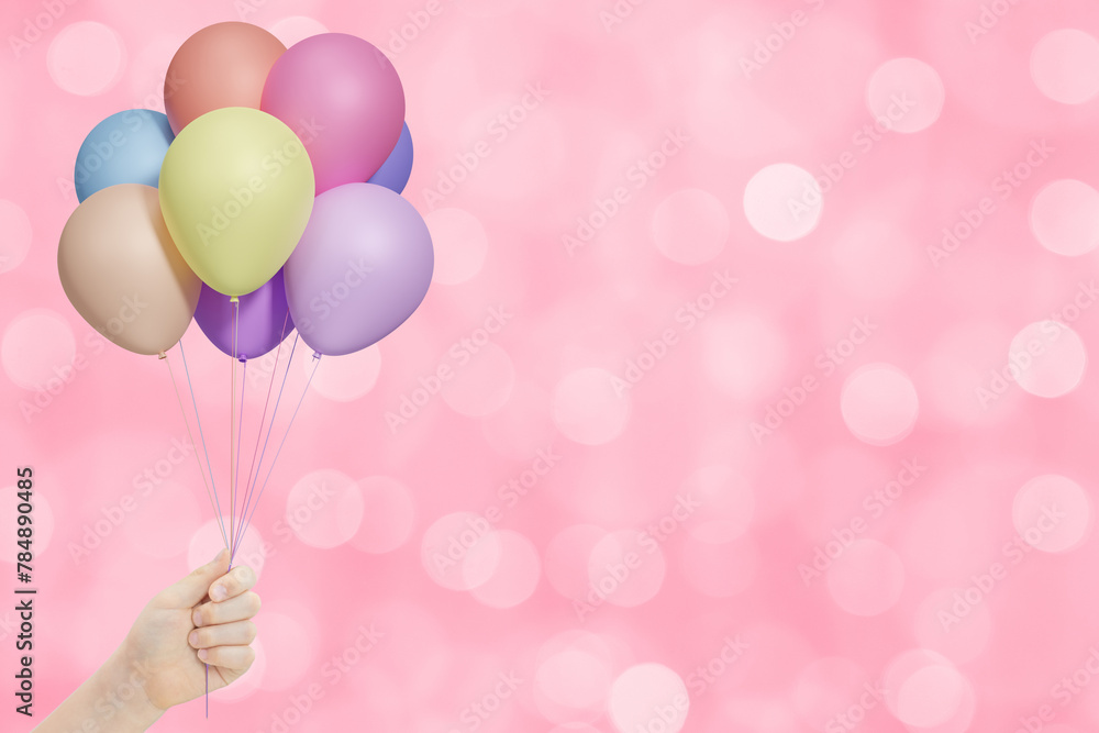 Poster female hand holds bunch of colorful balloons on pink blurred background. empty space for text