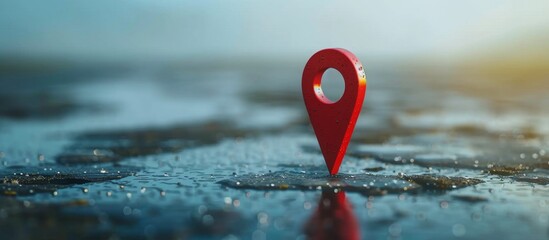 A single red pushpin placed on a wet and reflective surface