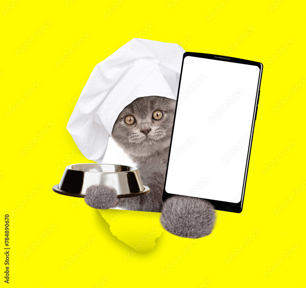 Aufkleber cute cat wearing chef's hat looks through a hole in yellow paper, holds empty bowl and shows smartph