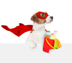 Happy jack russell terrier puppy wearing superhero costume holds bucket with washing fluids above empty white banner. Isolated on white background - 784891023