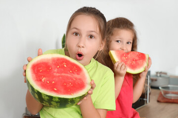 Shocked little girls eating fresh watermelon in kitchen