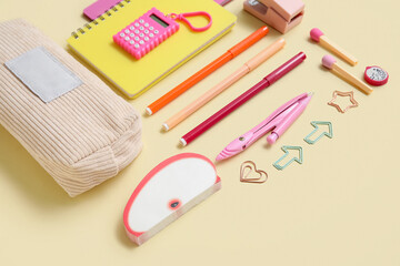 Pencil case with different school stationery and notebooks on beige background