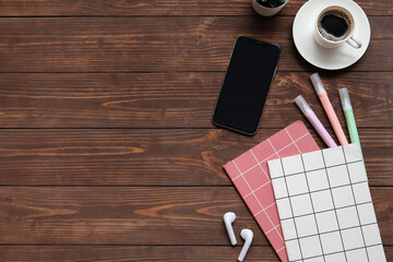 Phone, cup of coffee and stationery on wooden table