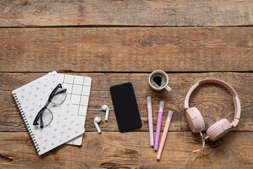 Phone, headphones, cup of coffee and stationery on wooden table