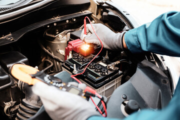 Close-up hand auto mechanic using meter to check car battery fail problem to change repairing and...