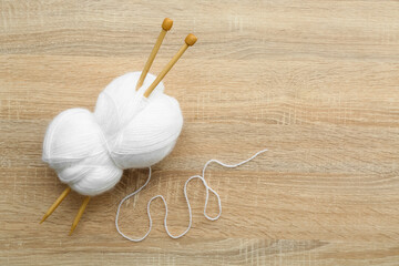 Yarn ball and knitting needles on wooden background