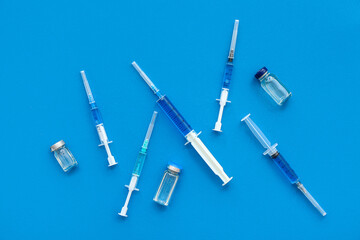 Medical syringes with medicine and ampoules on blue background