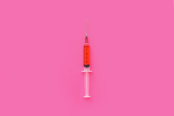 Medical syringe with blood on pink background