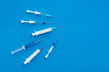 Medical syringes on blue background - obrazy, fototapety, plakaty