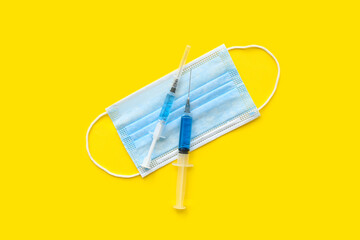 Fototapeta na wymiar Medical syringes with medicine and mask on yellow background