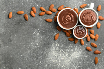 Bowls of tasty melted chocolate with almonds on grey grunge background