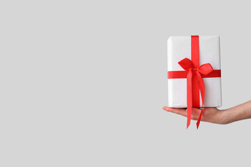 Female hand holding Christmas gift box on white background