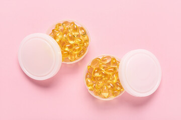 Boxes with fish oil capsules on pink background