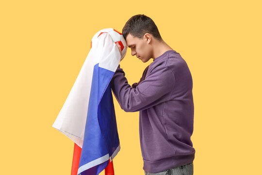 Young man with soccer ball and flag of France on yellow background