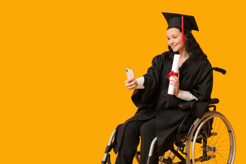 Beautiful female graduate student in wheelchair with graduation cap and diploma taking selfie on...