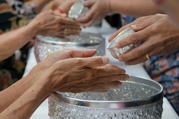 Pour water on the hands of revered group elders and ask for blessing. - obrazy, fototapety, plakaty