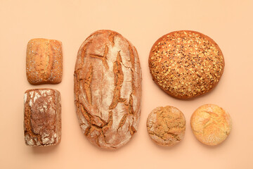 Loaves of fresh bread and buns on beige background