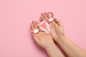 Female hands with paper uterus on pink background