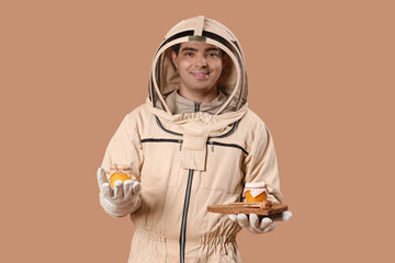 Male beekeeper with honey on brown background