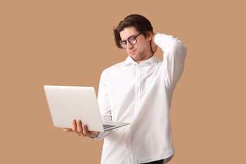Weary young businessman with laptop on beige background - obrazy, fototapety, plakaty