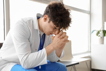 Stressed male medical intern sitting in clinic
