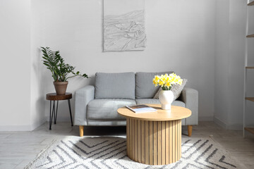 Vase with daffodils on table in interior of living room