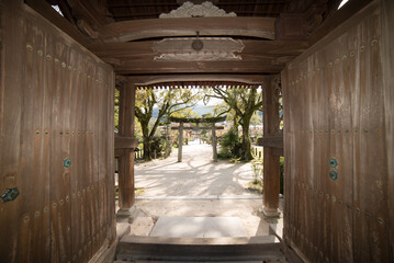 The entrance to a building is open, revealing a path leading to a courtyard japanese garden temple...