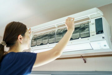 Asian woman cleaning a dirty air conditioner filter.