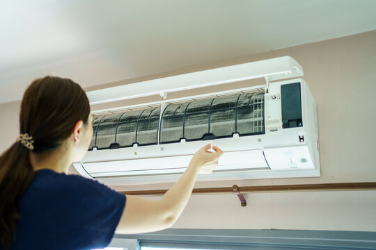 Asian woman cleaning a dirty air conditioner filter.