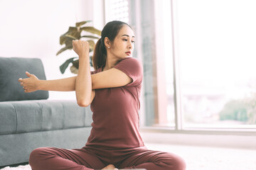 Adult asian woman stretching arms at home