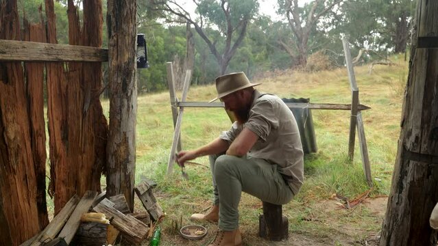 A bushman eating meat stew in a historical bark hut in the Australian bush.
