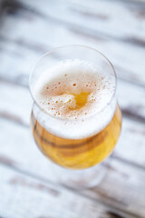 Glass of beer on bright wooden background. Copy space.