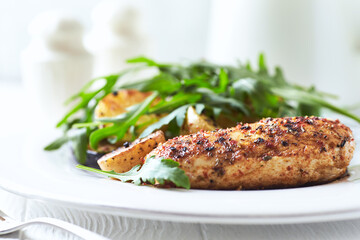 Grilled Chicken Breast with oven baked potatoes and fresh rocket. Bright background. Close up.