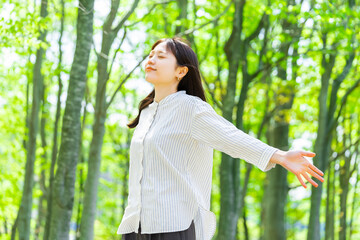 緑の中で深呼吸をする若い女性