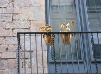 Golden plants decoration in the balcony with stone walls and windows in a town in Girona, Spain