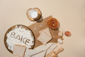 A minimals sense of baking ingredients and utensils on a pastel pink background decorated with croissant and sandwiches. Empty space for advertising with top view