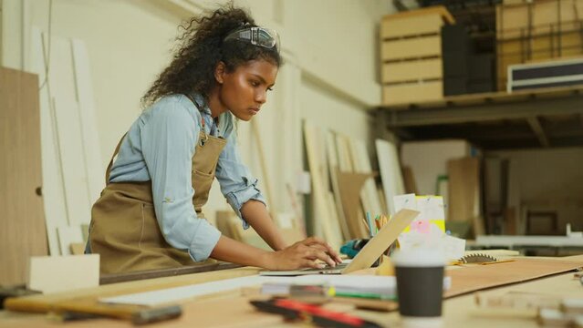 Professional carpenter or woodworker or charpentier woman use laptop to check the data about online selling product in workplace.
