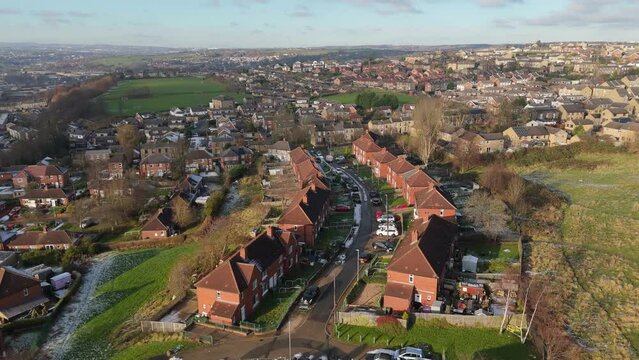 Drone's-eye winter view captures Dewsbury Moore Council estate's typical UK urban council-owned housing development with red-brick terraced homes and the industrial Yorkshire. Working class housing
