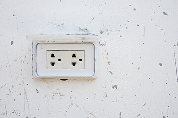 The electrical plug installed on the wall has cement stains.