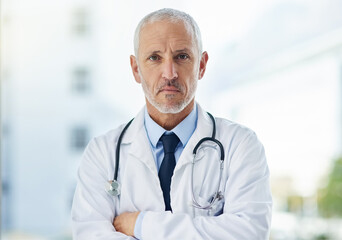 Doctor, serious and portrait of mature man in a hospital at a cardiology clinic with arms crossed. Professional, medical employee and stethoscope with healthcare, wellness and cardiologist consultant