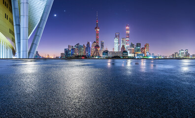 Asphalt road square and modern city buildings scenery at night in Shanghai. Asphalt pavement and city buildings after the rain.