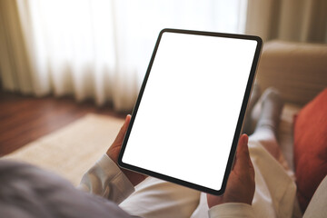 Mockup image of a woman holding digital tablet with blank desktop screen while sitting on a sofa at home - 784974077
