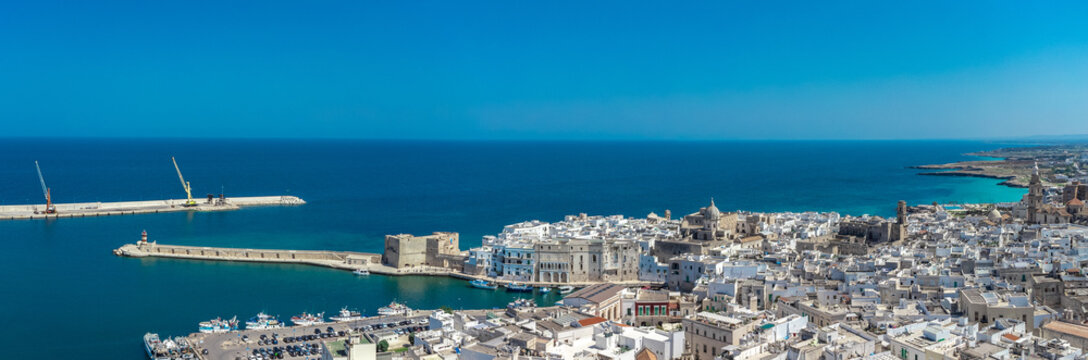 Wide drone panorama of the city of Monopoli on italian coast in Puglia region on a sunny spring day. Visible port and old houses
