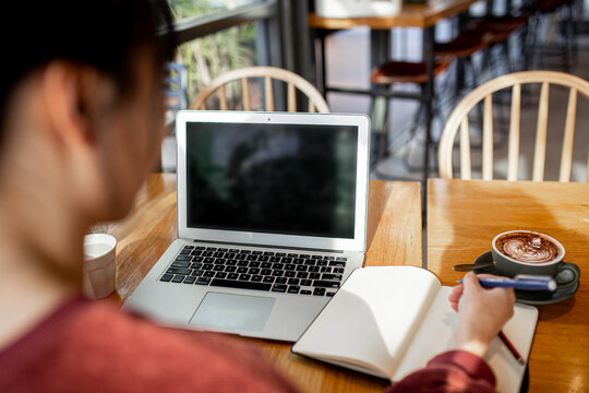 Asian small business owner working remotely on her laptop at a cafe