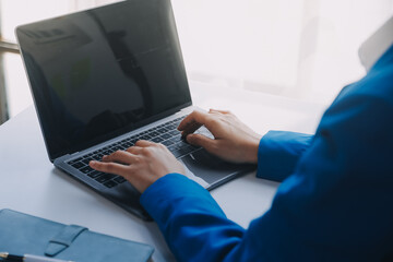 Cheerful business lady working on laptop in office, Asian happy beautiful businesswoman in formal suit work in workplace. Attractive female employee office worker smile.